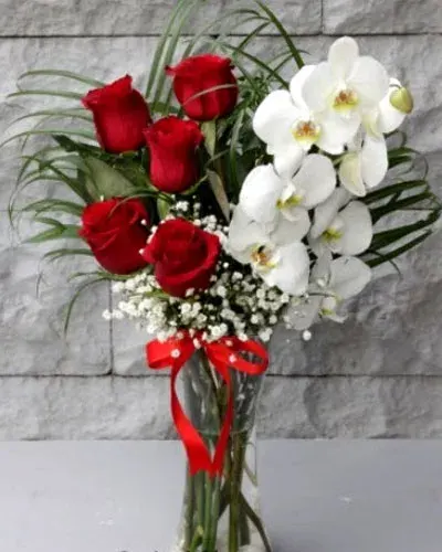 Orchidee und rote Rosen in der Glasvase